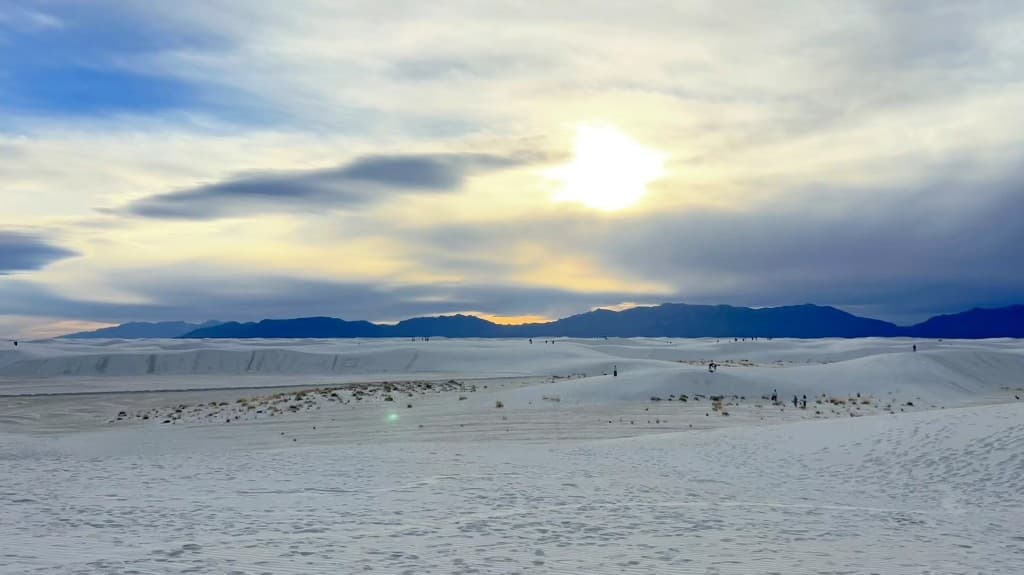 White Sands at sunset with soft light over distant mountain silhouettes.